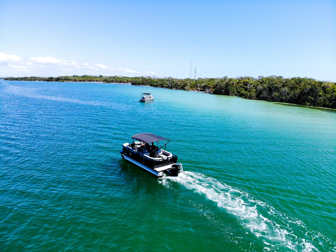 Aerial view of the pontoon underway leaving a wake across a deep blue channel
