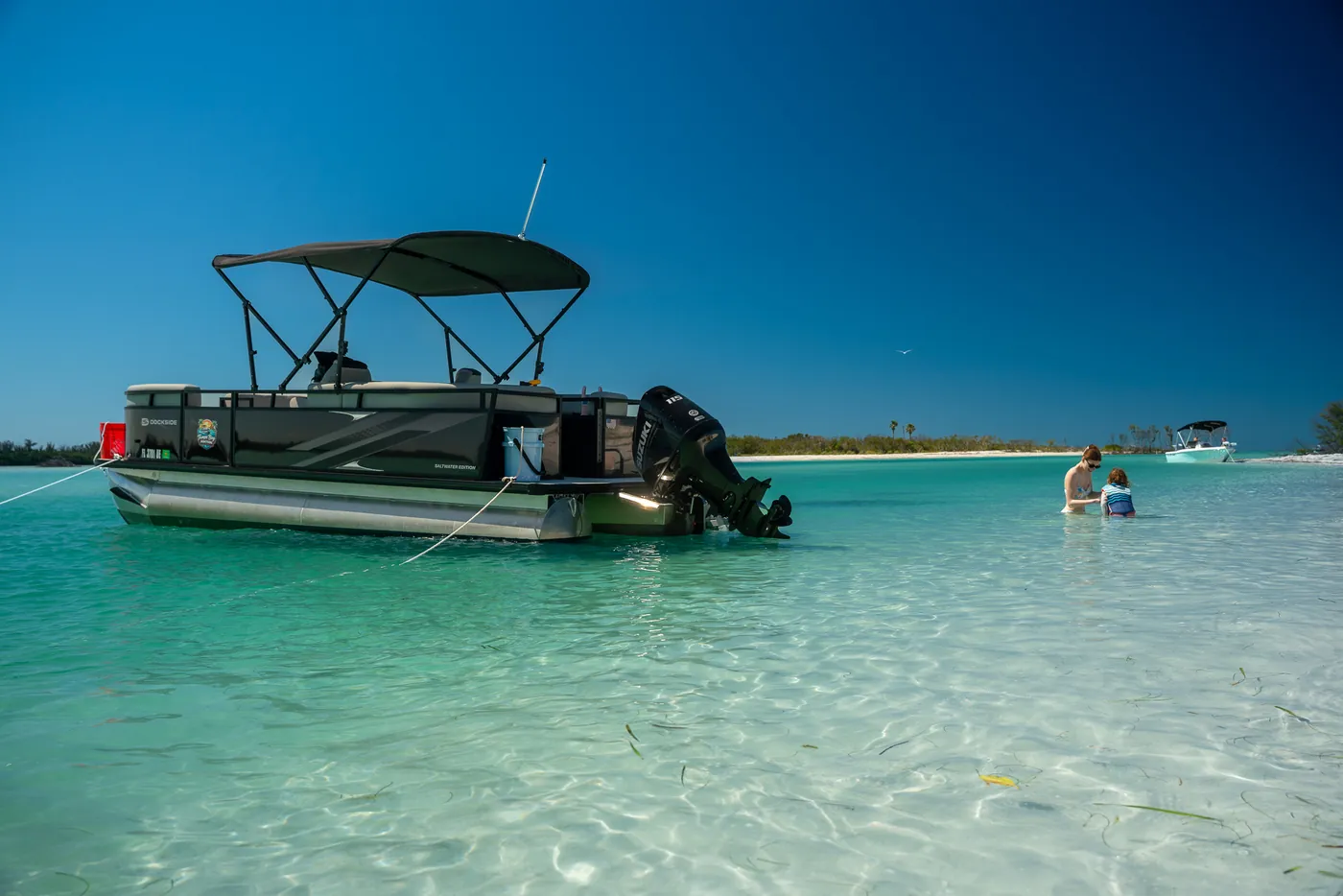 The 2026 TriToon anchored off a sandbar in shallow turquoise water on a clear day