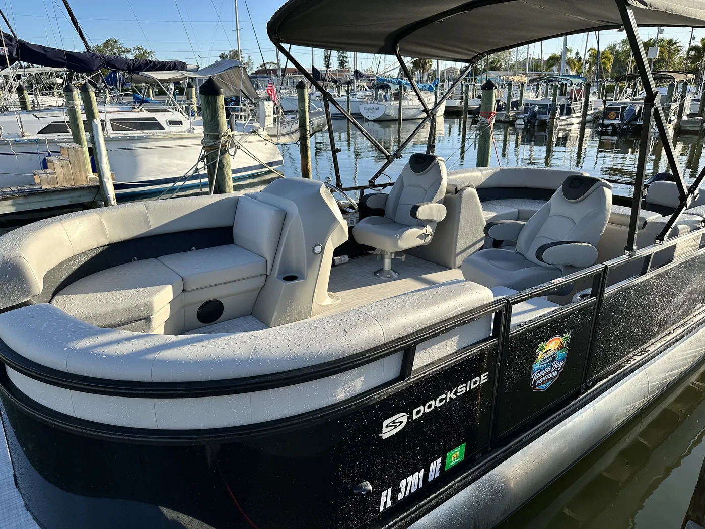 The helm station and passenger seating of the 2026 TriToon seen from the bow at the marina