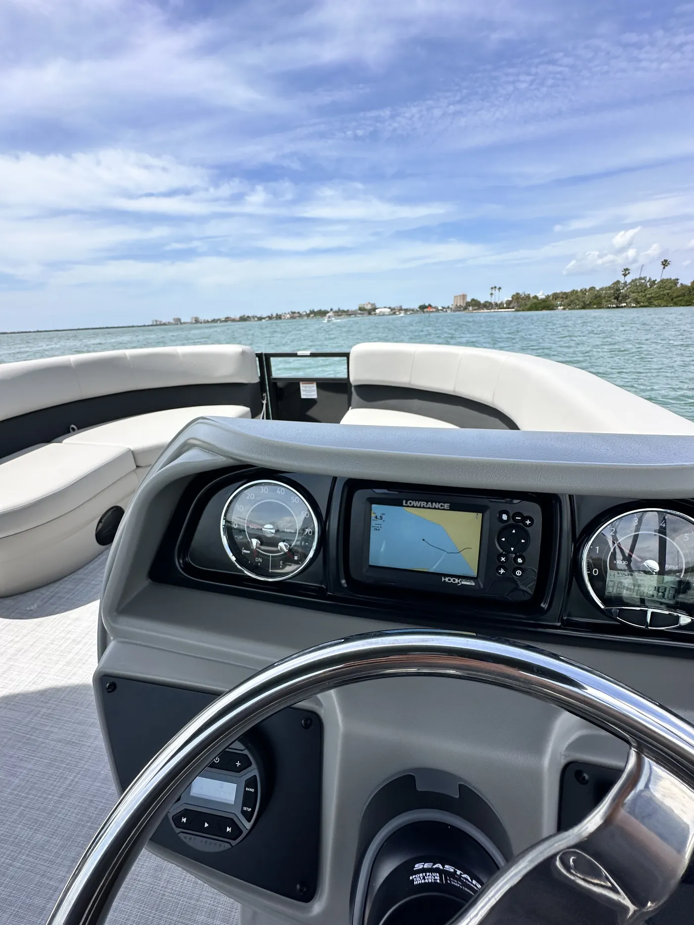 The pontoon helm console with steering wheel and chartplotter display while underway